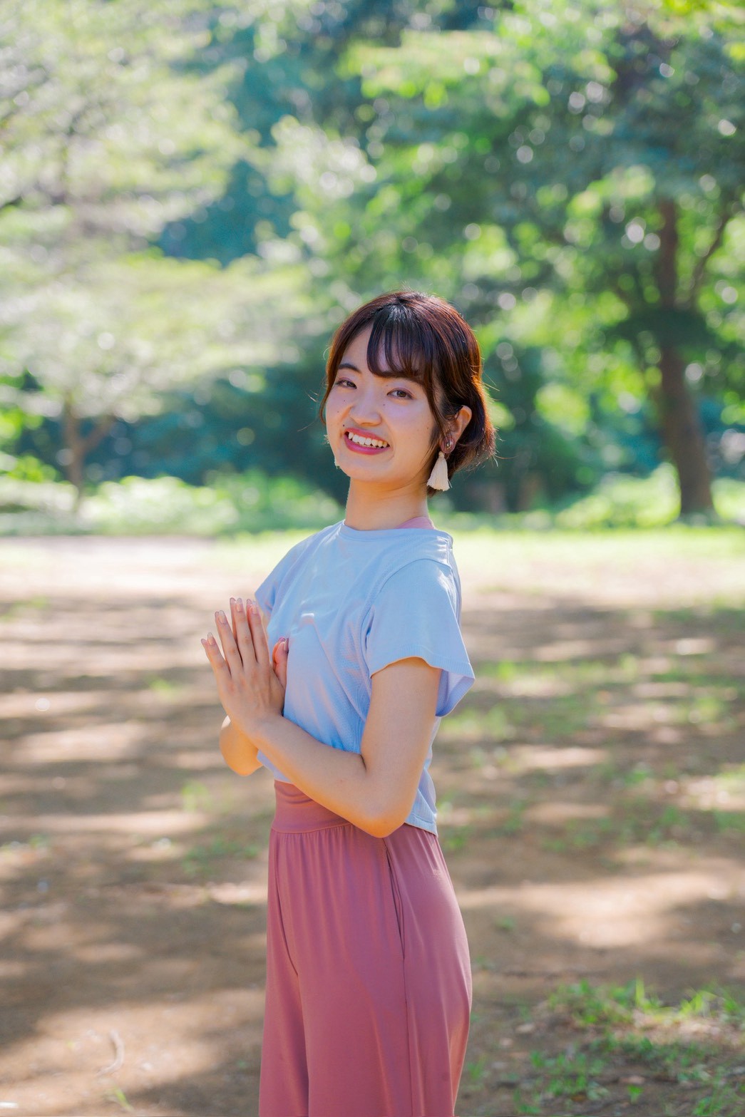 公園で合掌のポーズをとるRINAさん